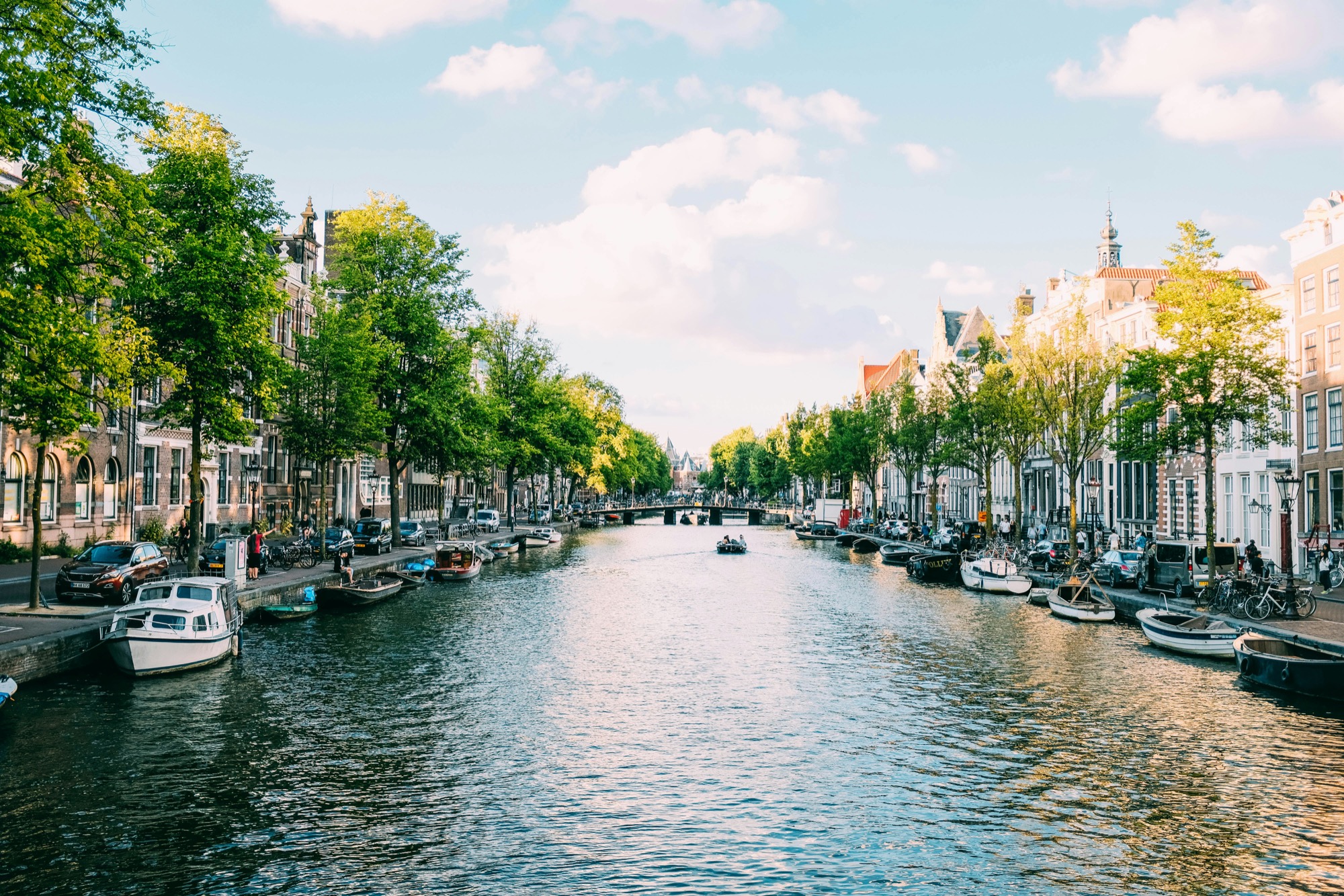 Amsterdam canal with boats and tree-lined Dutch canal houses